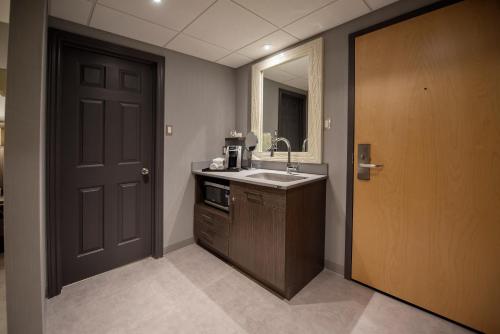 a bathroom with a sink and a mirror and a door at Hôtel & Suites Le Dauphin Québec in Quebec City