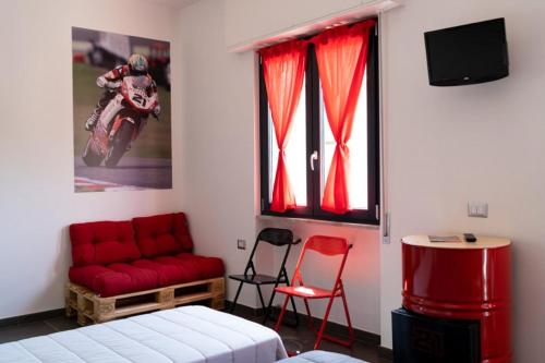 um quarto com uma cama e um sofá vermelho em Italian Piston House Sport Moto Rent em Millesimo