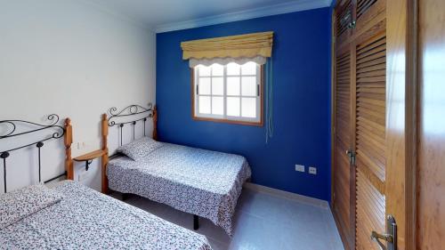 a blue room with two beds and a window at Mi Posadita - Salto Ángel in Playa de San Juan