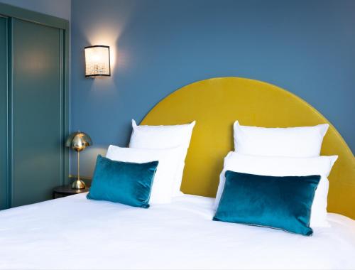 a bed with blue and white pillows on it at Hotel Mercure Roscoff Bord De Mer in Roscoff