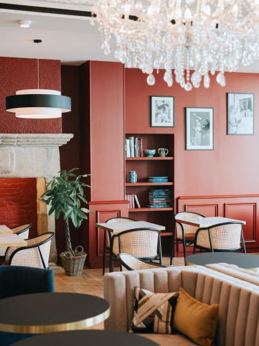 a restaurant with tables and chairs and a chandelier at Hotel Mercure Roscoff Bord De Mer in Roscoff