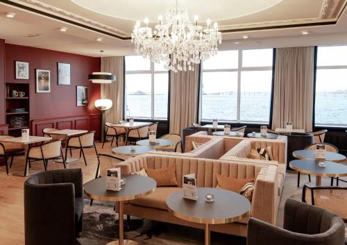 a living room filled with furniture and tables at Hotel Mercure Roscoff Bord De Mer in Roscoff