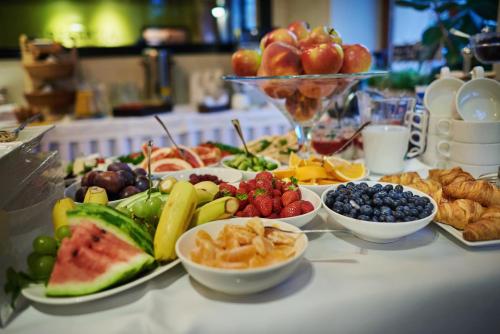 a table topped with plates of fruit and other foods at Hotel Fado Spa & Restaurant in Świdnica