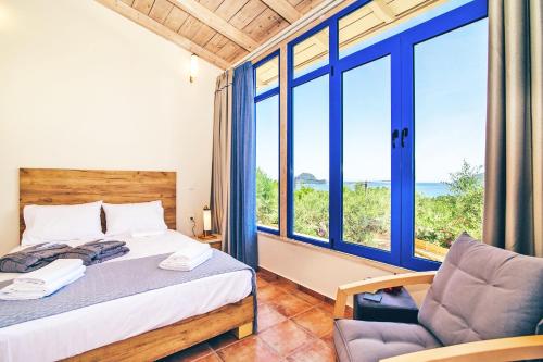 een slaapkamer met een bed, een stoel en ramen bij Villa Vakis in Lithakia