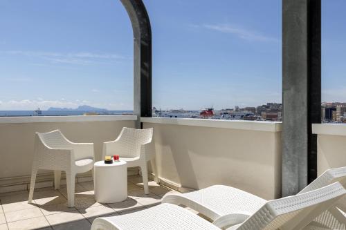 a balcony with white chairs and a table with a view at Palazzo Salgar in Naples