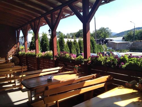 a group of wooden benches under a pavilion with flowers at Finezja Wiedeńska in Stronie Śląskie