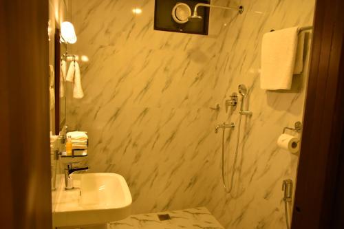 a white bathroom with a sink and a shower at Gaia Holiday Home in Dhulikhel
