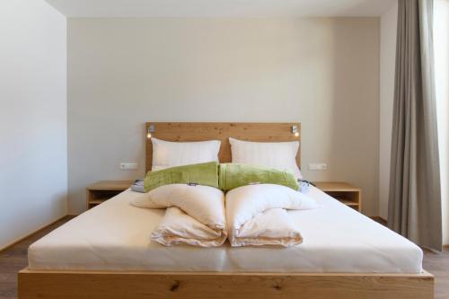 a bed with white sheets and green pillows at Almstüble Bergfrieden in Damuls