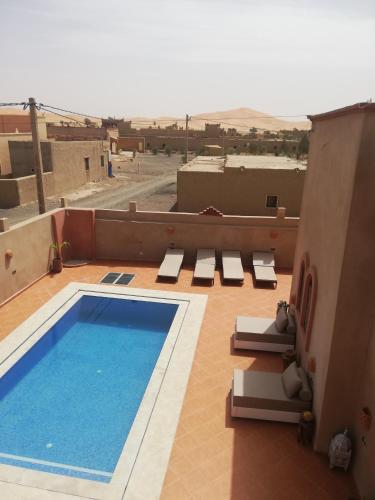 a swimming pool on top of a building with chairs at Riad Dar Poublanc in Merzouga