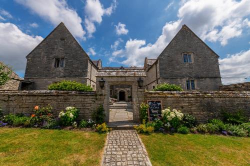 an old stone house with a brick wall at Mortons Manor in Corfe Castle