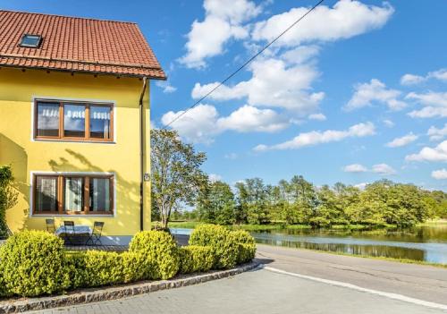 a yellow house with bushes in front of a river at Bartlhof-Ferienwohnungen-Zimmer in Burglengenfeld