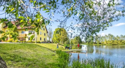 a house next to a lake with people walking a dog at Bartlhof-Ferienwohnungen-Zimmer in Burglengenfeld