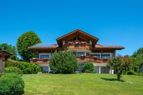 a large house with a roof on a green field at Aparthotel Werdenfels in Murnau am Staffelsee