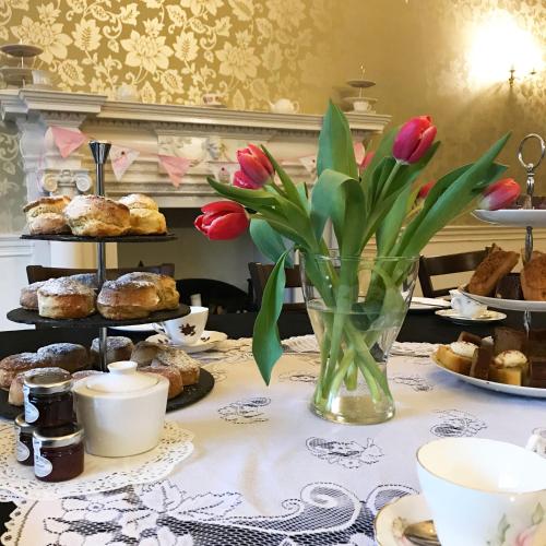 a table with a vase of flowers and pastries at Donington Manor Hotel in Castle Donington