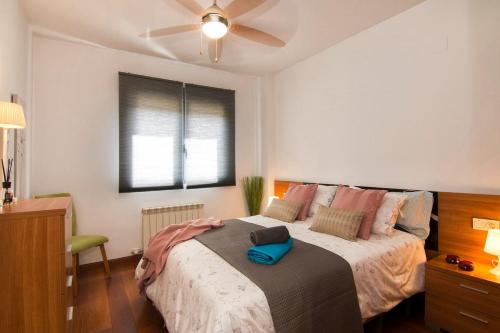a bedroom with a large bed with a ceiling fan at Apartamento Fórum-Ciencias con Piscina, Gym & Parking in Granada