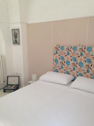 マンドゥーリアにあるbb dragonetti holiday home salentoの- 花のヘッドボード付きの白いベッド1台が備わるベッドルーム
