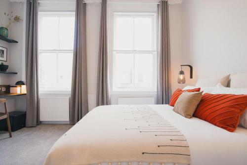 una camera da letto con un grande letto bianco con due finestre di D8 - Shoreditch a Londra