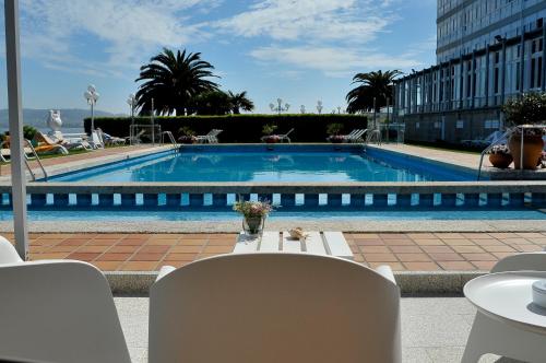 a large swimming pool with a table and chairs and a table and chairs at Eurostars Louxo Talaso in Isla de la Toja