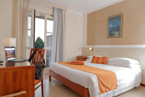 a bedroom with a bed and a desk and a computer at Hotel Michelangelo in Terranuova Bracciolini