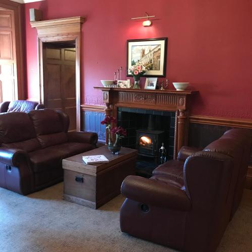 a living room with two chairs and a fireplace at Ashtree House Hotel, Glasgow Airport & Paisley in Paisley