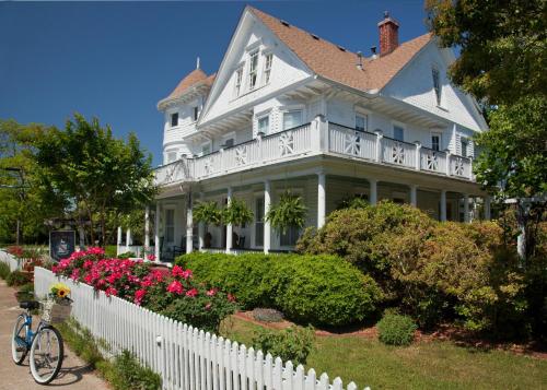 a white house with a white fence and flowers at White Doe Inn Bed & Breakfast in Manteo