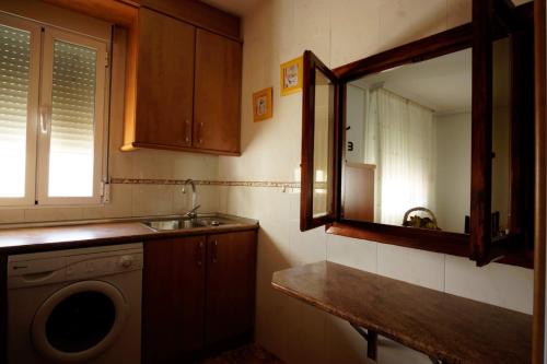 a kitchen with a sink and a washing machine at LA CASA DEL MONTE in Granja Llumes