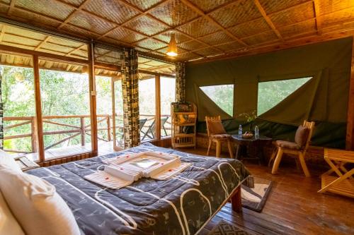 a bedroom with a bed in a room with windows at Rushaga Gorilla Lodge in Bugambira