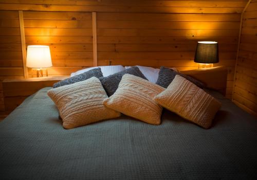 a bed with three pillows on it with two lamps at Rakši in Cēsis