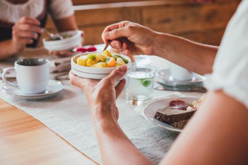 a group of people sitting at a table eating food at Agriturismo Maso Corradini in Castello di Fiemme