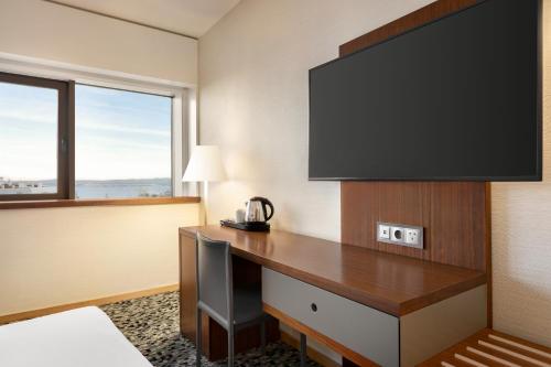 a hotel room with a desk with a flat screen tv at Ramada by Wyndham Lisbon in Lisbon