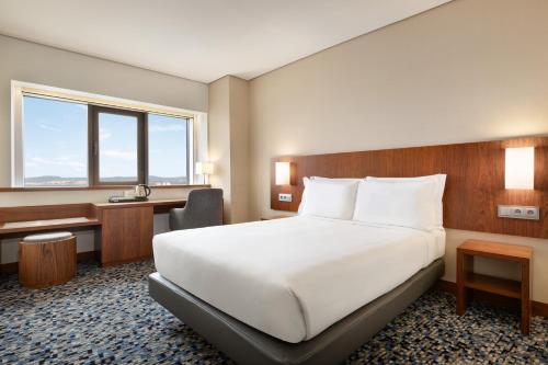 リスボンにあるRamada by Wyndham Lisbonの大きなベッドと机があるホテルの部屋