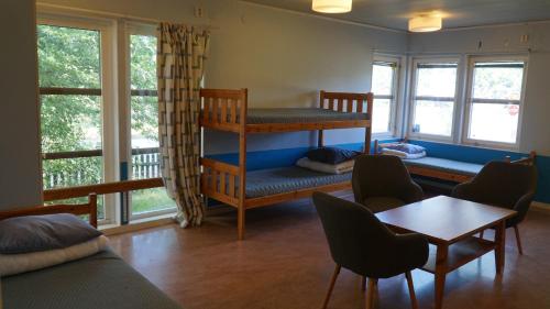 ストックホルムにあるBredängs Hostelの二段ベッド、テーブル、椅子が備わる客室です。