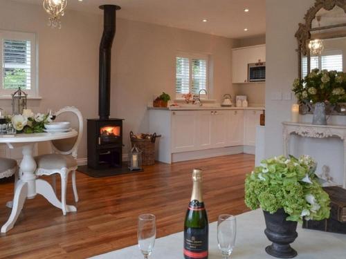 a living room with a fireplace and a table with a bottle of wine at The Pavilion at Brunger House in Tenterden