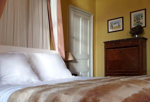 a bedroom with a white bed and a wooden cabinet at Chateau LE BROSSAY in Renac