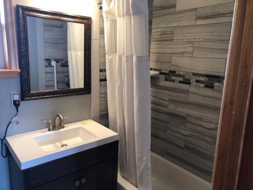 a bathroom with a sink and a mirror and a shower at Rainbow Lodge and Inn in Colorado Springs