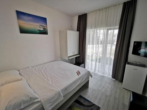 a bedroom with a bed and a large window at Vila Tropicana in Eforie Sud