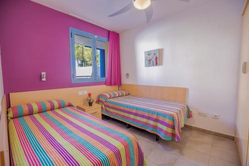 2 camas en una habitación con paredes rosas y moradas en Rentalmar Costa Verde, en Cambrils