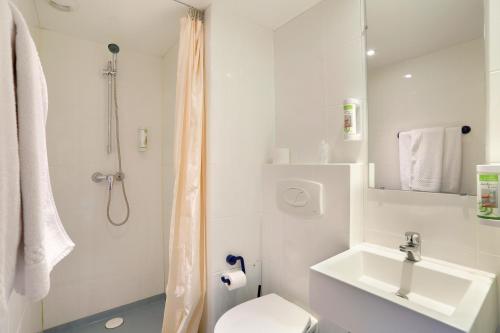 a white bathroom with a toilet and a sink at Grand Hotel Sénia - Paris Orly Airport in Orly
