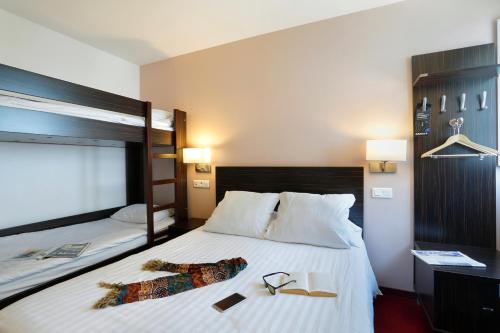 a hotel room with a bed with a pair of glasses on it at Grand Hotel Sénia - Paris Orly Airport in Orly
