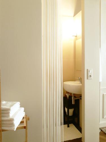 La salle de bains est pourvue d'un lavabo et d'un rideau de douche blanc. dans l'établissement Le85 Paris, à Paris
