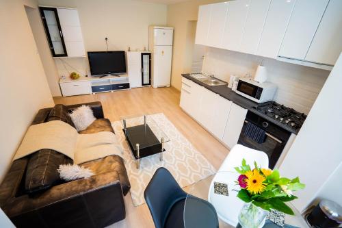 a kitchen and a living room with a couch and a table at Cris Apartament in Suceava