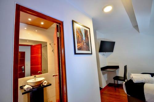 ein Bad mit einem Waschbecken, einem Bett und einem Spiegel in der Unterkunft Ankawa Hotel Boutique in Cusco