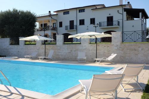 uma piscina com cadeiras e guarda-sóis ao lado de um edifício em Villa Torre Cantore em Rotondella