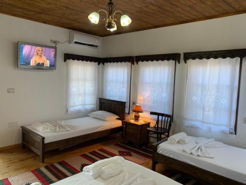 a bedroom with two beds and a tv on the wall at Guest House Genti in Berat