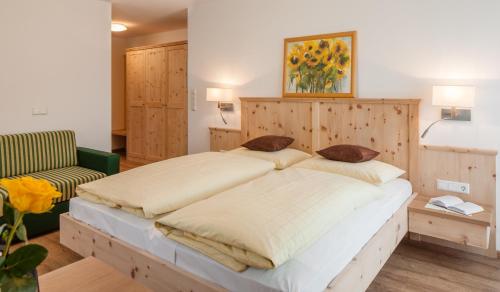 a bedroom with a large bed with a wooden headboard at Garni Appartment Wagnerhof in Rablà