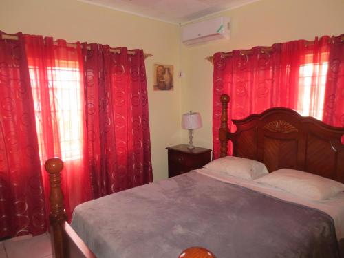 a bedroom with red drapes and a bed with a bed sidx sidx sidx at Chateau Yellow in Mandeville