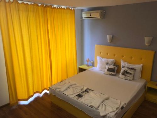 a bedroom with a bed with yellow curtains at Guest House Stels in Kranevo