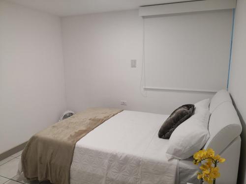a bedroom with a white bed and a couch at Apartments and Rooms Distecon in Guatemala