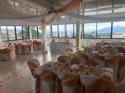 a banquet hall with tables and chairs in a room with windows at Hotel Santa Monica in Fusagasuga
