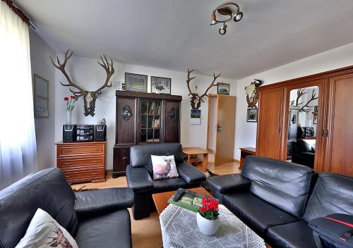 a living room with black leather furniture and antlers on the wall at Apartamenty w Puszczy Boreckiej in Kruklanki